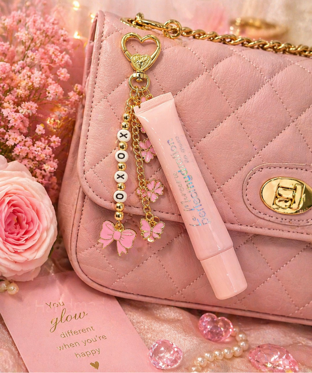 Pink handbag with decorative charm and pink lip balm, surrounded by flowers and decorative elements.